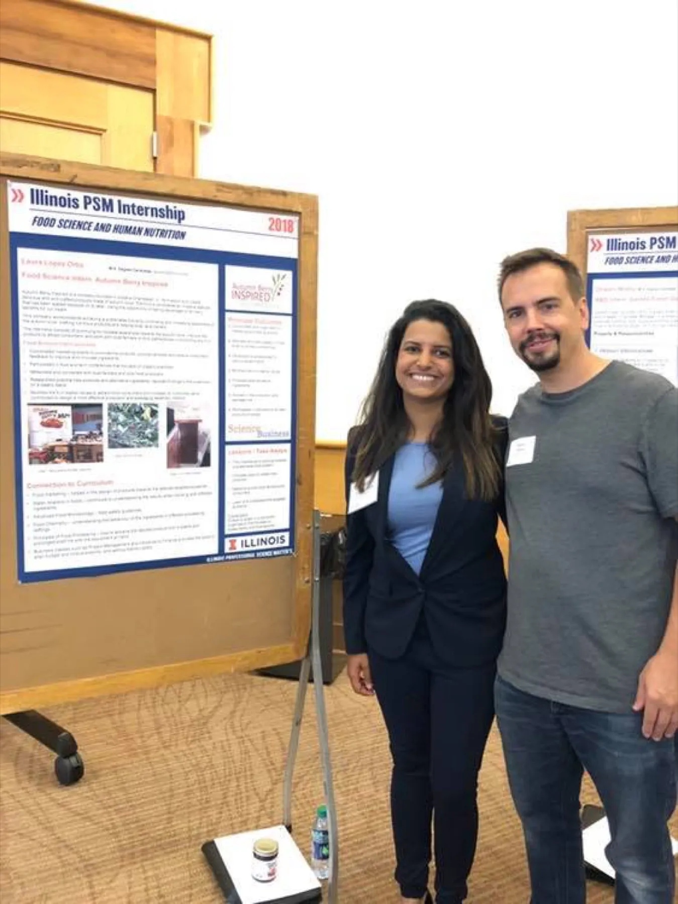 Dustin Kelly with an intern beside a research poster at an internship showcase.